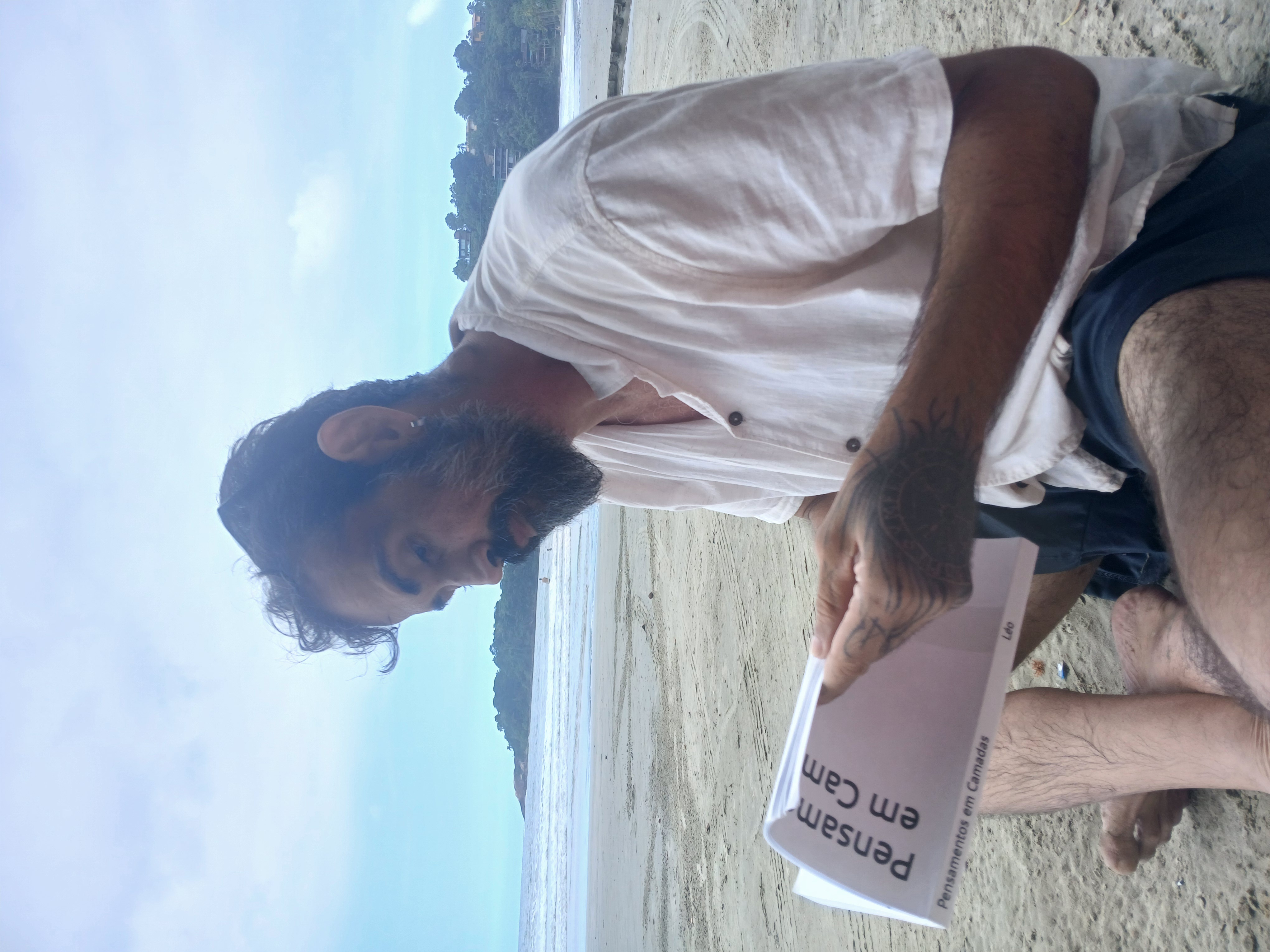 Léo Barros segurando a primeira edição de Pensamentos em Camadas na praia